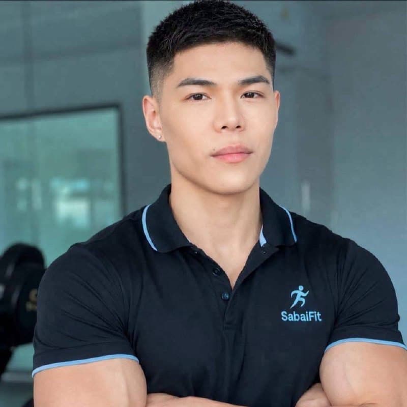 A SabaiFit personal trainer in a gym, arms crossed, wearing a SabaiFit polo shirt